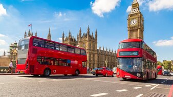 Londoner Straße mit roten Doppeldeckerbusen und im Hintergrund befindet sich der Big Ben